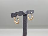 a pair of gold hoop earrings on a black stand