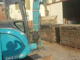 a blue excavator that is parked in front of a building