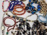 many different types of necklaces and bracelets laid out on a table