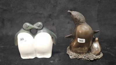 two figurines of penguins on a black background