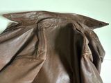 brown leather jacket hanging on a wall next to a white wall