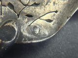 a close up of a silver spoon with a flower design on it