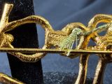 a close up of a gold brooch with a bird on it