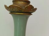 a green vase with a gold lid sitting on a table