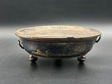 an old metal bowl sitting on top of a black table