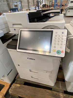 une imprimante et un scanner-imprimante posés sur une palette dans un entrepôt