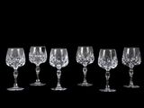 six wine glasses are lined up in a row on a black background