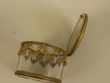 a small glass container with a gold decoration on it