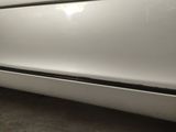 the front bumper of a white car with a black stripe on it