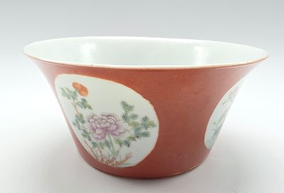 un bol rouge orné de fleurs, posé sur un fond blanc