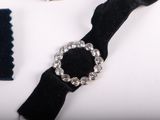a black watch and a black velvet bracelet on a white surface