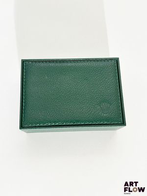 une photo d'un portefeuille en cuir vert posé sur une surface blanche