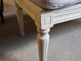 a white foot stool with a cushion on top of it