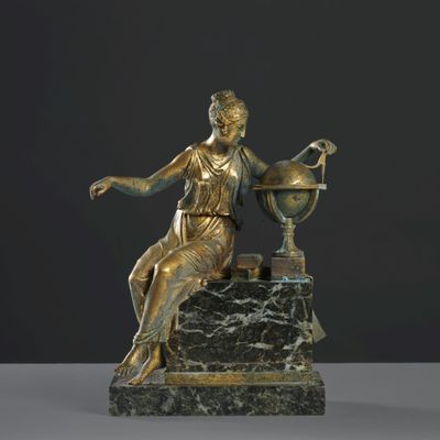 statue en bronze représentant une femme assise sur un rocher, tenant un globe terrestre
