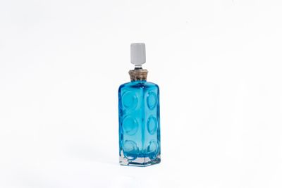 une bouteille en verre bleue avec un bouchon blanc, posée sur une surface blanche