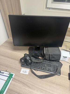 un écran d'ordinateur et un clavier posés sur un bureau, à côté d'un téléphone portable