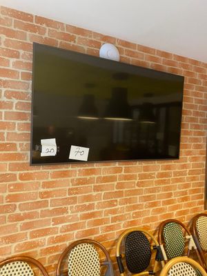 a television mounted on a brick wall above a row of chairs