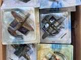 Six petits avions miniatures se trouvent dans une boîte en carton posée sur une table.