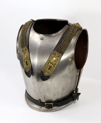 une armure argentée et dorée exposée sur un socle blanc