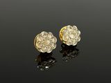 a pair of gold and diamond earrings on a black surface