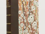 un vieux livre à la couverture marron, ornée d'un motif de crânes