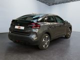 the rear end of a grey car in a white room