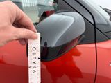 a hand that is holding a measuring tape in front of a car