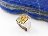 un gros plan sur une bague posée sur un rocher, avec une pierre en arrière-plan