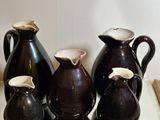 five vases sitting on a table with a mirror behind them