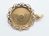 a close up of a gold pendant on a white surface