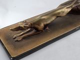 bronze sculpture of a dog laying down on a wooden base