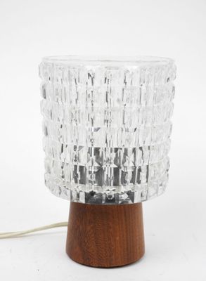 a close up of a glass lamp on a wooden base