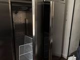 des réfrigérateurs et des congélateurs en acier inoxydable dans une cuisine dont le sol est recouvert d'un carrelage à damier noir et blanc