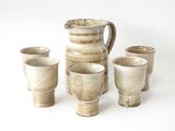 quatre tasses et un pichet posés les uns à côté des autres sur une table