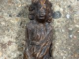 une statue en bois représentant une femme assise par terre