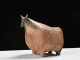 une petite statue représentant une vache assise sur une table