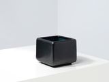 un vase carré noir posé sur une table blanche