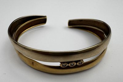 a close up of a gold cuff with a diamond on it