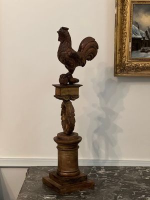 une statue de coq posée sur un socle dans une pièce