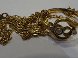 a gold chain with a ring on it on a white surface