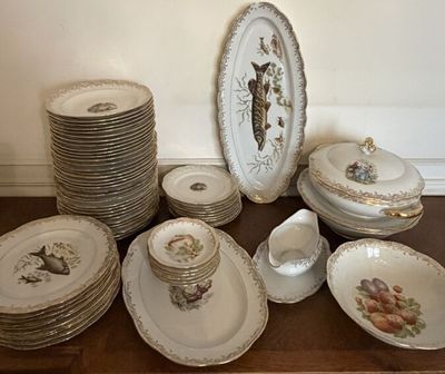 many plates and bowls on a table with a clock on the wall