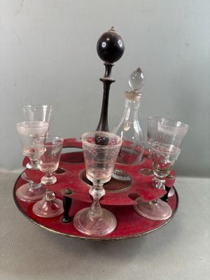 des bouteilles et des verres posés sur un plateau, sur une table où se trouve une lampe