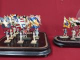 two miniature figurines of soldiers with flags on them