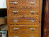 a tall wooden chest of drawers in the corner of a room