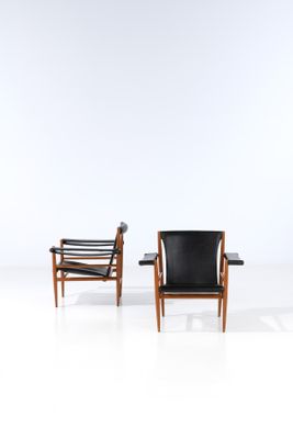 two black leather chairs in a white room with a white wall