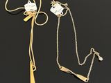 two gold necklaces and a chain with a tag on it