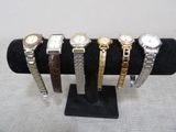six watches on display on a black display stand on a white background
