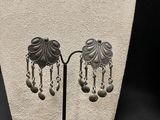 pair of silver earrings with dangling beads on a black stand