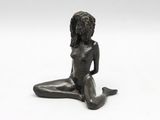 bronze statue of a woman sitting on the ground