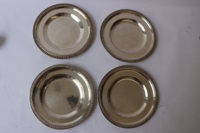 four silver plates on a white table with a white background